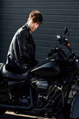 Fototapeta na wymiar young motorcyclist in black leather jacket sitting on motorcycle