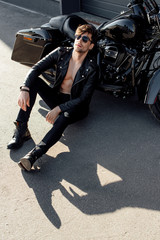 Fototapeta na wymiar young man relaxing while sitting on ground near black motorcycle
