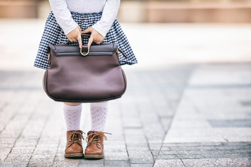 Little girl wearing uniform with a school bag, close up photo, back to school