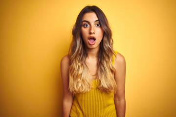 Young beautiful woman wearing t-shirt over yellow isolated background afraid and shocked with surprise and amazed expression, fear and excited face.