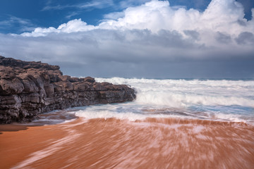 waves crashing on sand and rock