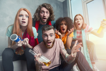 Fototapeta premium Happy friends of football fans watching soccer on tv and celebrating victory
