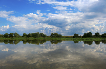 Obraz na płótnie Canvas Beautiful summer landscape in Russia. Mirror reflection of the sky and clouds in the water of the lake