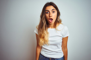 Fototapeta premium Young beautiful woman wearing casual white t-shirt over isolated background afraid and shocked with surprise and amazed expression, fear and excited face.