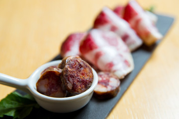 Smoked meat antipasto platter. Cutting board with prosciutto, salami,bread on dark stone background.