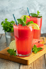 Watermelon slushie with lime and mint, summer refreshing drink in tall glasses on a light blue background. Sweet cold smoothie