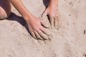 childish hands playing in the sand