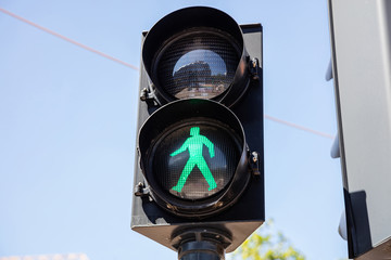 Pedestrian green traffic light on blue sky background