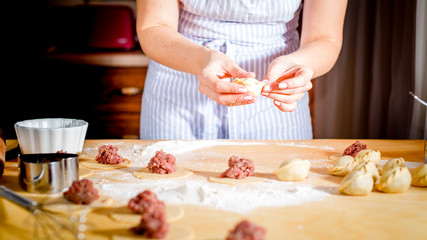 woman makes dumplings at home on kitchen table, close up