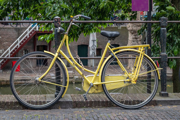 Yellow bike color locked on a river canal rail in Utrecht city, Netherlands