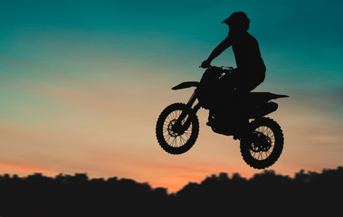 Motocross Dirt Bike rider getting air off of jump at sunset
