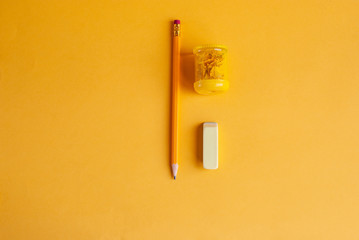 Bright yellow pencil with sharpener and eraser for studying, drawing, hobby on a yellow background.