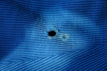 a piece of blue old cloth with a black hole on the clothes