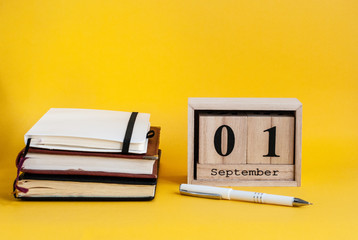 Wooden calendar with the date of September 1 next is a stack of notebooks