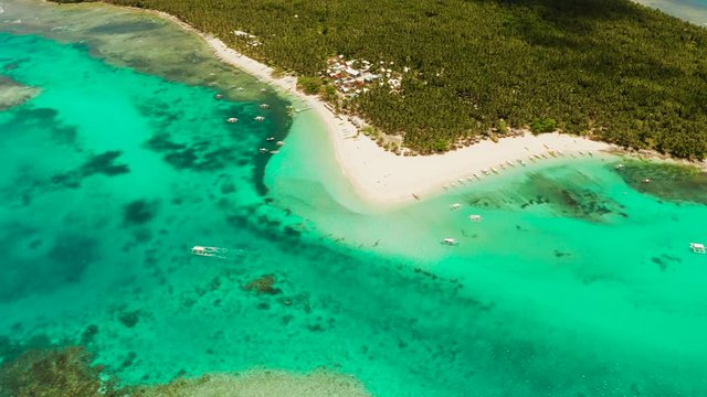 Sandy beach with tourists, palm trees and turquoise water on the island of Daco, Philippines, aerial view. Summer and travel vacation concept