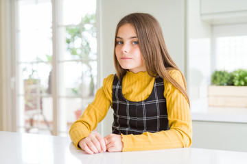 Young beautiful blonde kid girl wearing casual yellow sweater at home skeptic and nervous, frowning upset because of problem. Negative person.