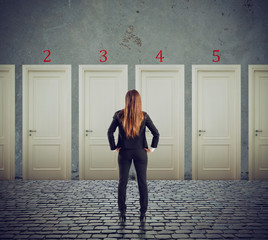 Businesswoman looking to select the right door. Concept of confusion and competition