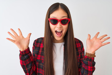 Young chinese woman wearing casual jacket and sunglasses over isolated white background very happy and excited, winner expression celebrating victory screaming with big smile and raised hands