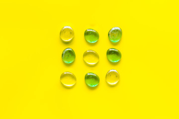 Shiny glass stones for decoration, creativity and craft on yellow background top view