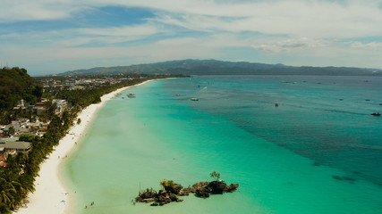 White sand beach and Willy's rock with tourists and hotels and sailing boat, aerial view. Boracay, Philippines. Summer and travel vacation concept.