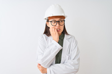 Young chinese engineer woman wearing coat helmet glasses over isolated white background looking stressed and nervous with hands on mouth biting nails. Anxiety problem.