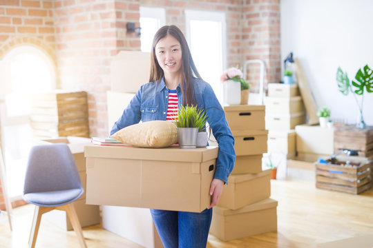 Beautiful asian young woman holding boxes, smiling happy moving to a new home