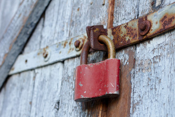 Old brown padlock on a gray door with wooden planks of cracked paint and rust. Vintage gates with...