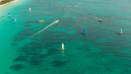 Sailing boats in crystal clear turquoise water, from above. Sailing yacht glides over the waves, Boracay, Philippines.