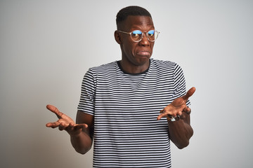 African american man wearing striped t-shirt and glasses over isolated white background clueless...