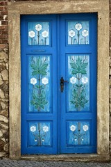 Painted wooden entrance door. Entrance to the historic house stylishly decorated with floral pattern. Vintage look.