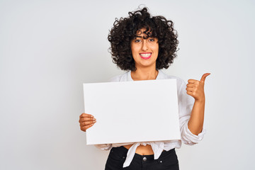 Young arab woman with curly hair holding banner over isolated white background happy with big smile doing ok sign, thumb up with fingers, excellent sign