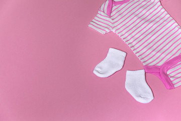 Baby clothes for newborn on a pink background with copy space on the left