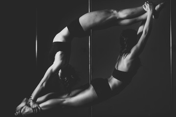 silhouette of two pole dancer women in action.