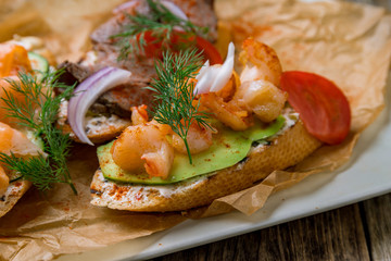 Bruschetta with prawns and avocado on wooden table