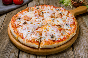Pizza with ham and mushrooms on wooden table