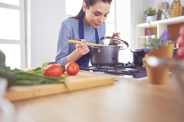 Cooking woman in kitchen with wooden spoon