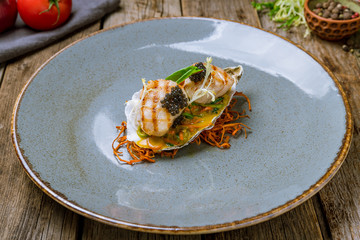 grilled scallop with black caviar on wooden table