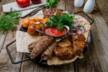 platter of different kebabs on wooden table