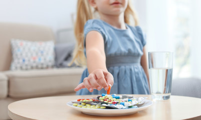 Obraz na płótnie Canvas Little child taking pill from plate at home. Household danger