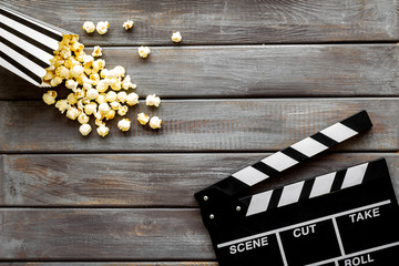 Watch film in cinema with popcorn and clapperboard on wooden background top view