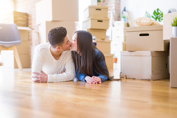 Fototapeta na wymiar Young asian couple lying on the floor of new house arround cardboard boxes relaxing and smiling happy