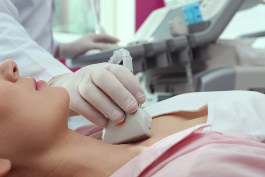 Doctor conducting ultrasound examination of thyroid gland in clinic, closeup