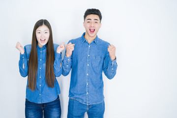 Beautiful young asian couple over white isolated background celebrating surprised and amazed for success with arms raised and open eyes. Winner concept.