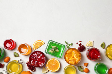Flat lay composition with different jelly desserts on light background, space for text