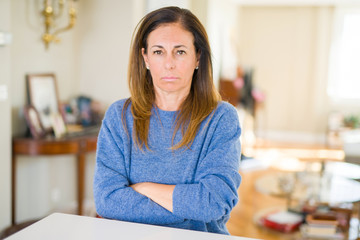 Beautiful middle age woman at home skeptic and nervous, disapproving expression on face with crossed arms. Negative person.