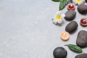 Composition with spa stones and lit candles on grey marble background, space for text