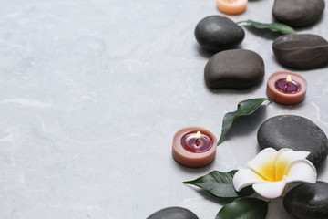 Composition with spa stones and lit candles on grey marble background, space for text