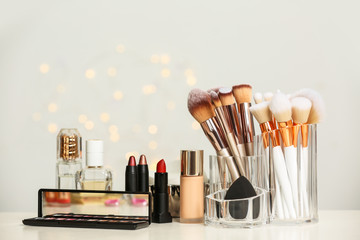 Set of cosmetic products and makeup brushes on dressing table