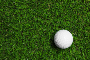 Golf ball on green artificial grass, top view with space for text