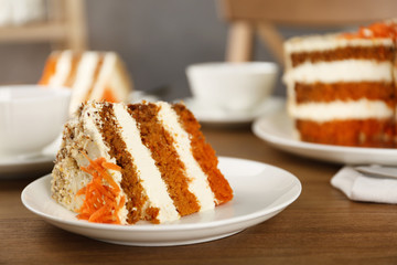 Plate with piece of carrot cake on wooden table, space for text
